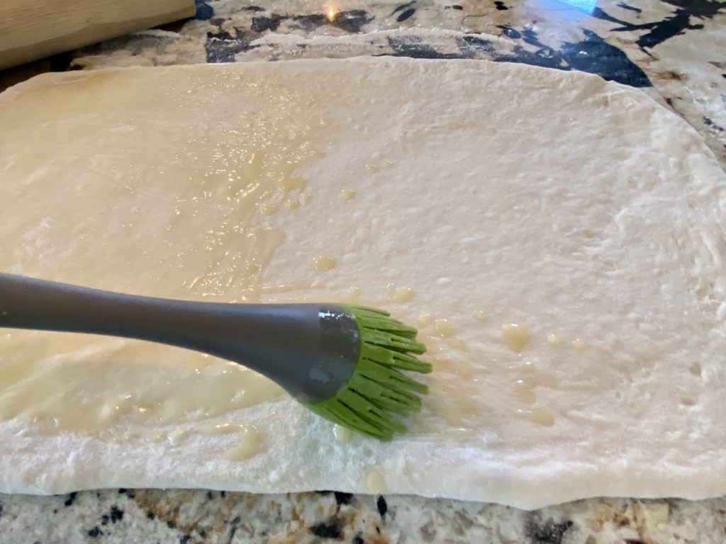 Brushing the dough with melted butter.
